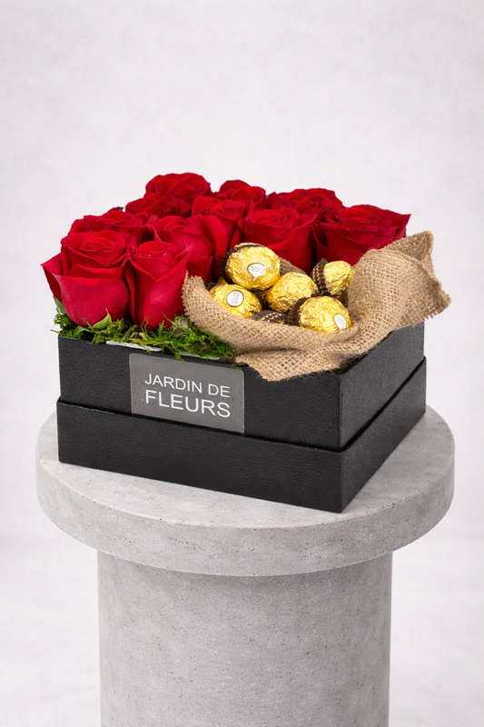 Box of red roses with chocolates on a gray pedestal against a white background