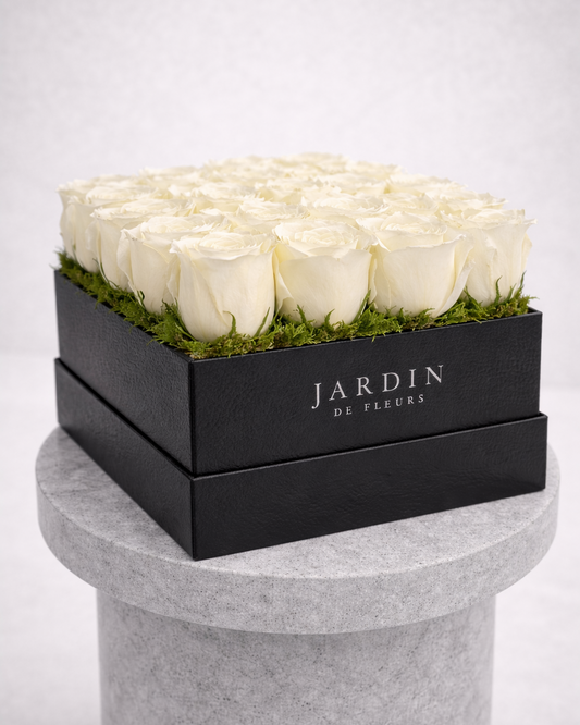 Black box with white roses and 'Jardin de Fleurs' branding on a gray pedestal.