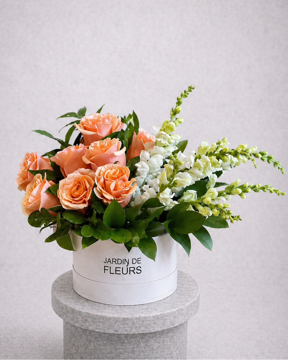 Floral arrangement in a white box labeled 'Jardin de Fleurs' on a gray pedestal against a light gray background.