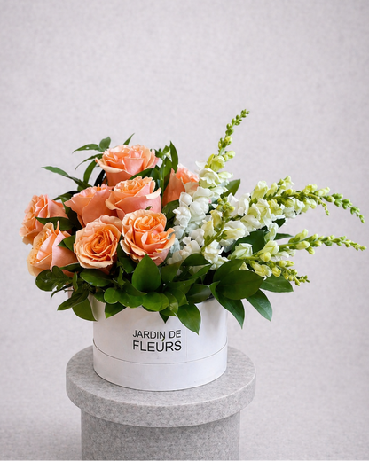 Floral arrangement in a white box labeled 'Jardin de Fleurs' on a gray pedestal against a light gray background.