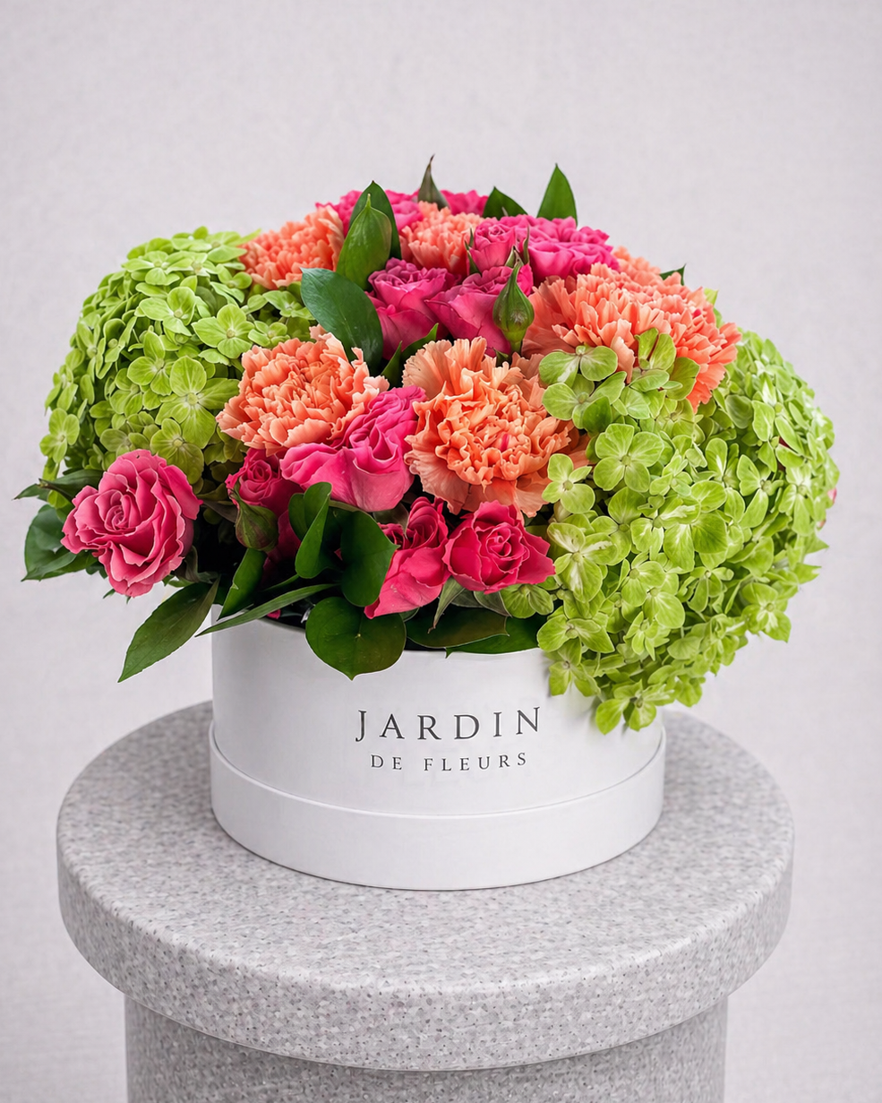 Colorful bouquet of flowers in a white box with 'Jardin de Fleurs' branding on a gray pedestal.