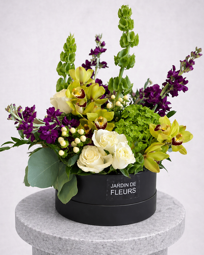 Floral arrangement in a black box labeled 'Jardin de Fleurs' on a gray pedestal.