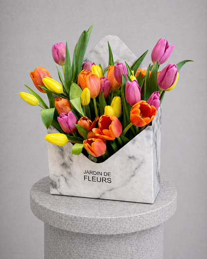 Bouquet of colorful tulips in a marble-patterned box labeled 'Jardin de Fleurs' on a gray background.