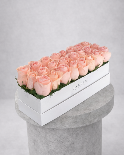 Box of pink roses on a gray pedestal with a light gray background