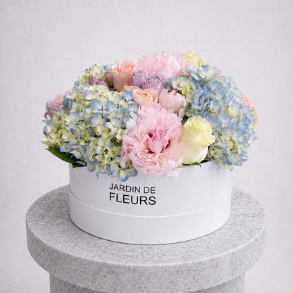 Floral arrangement in a white box with 'Jardin de Fleurs' text on a gray pedestal.
