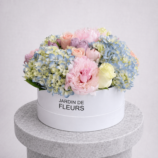 Floral arrangement in a white box with 'Jardin de Fleurs' text on a gray pedestal.