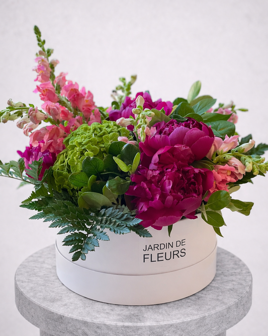 Floral arrangement in a white box labeled 'Jardin de Fleurs' on a gray pedestal.