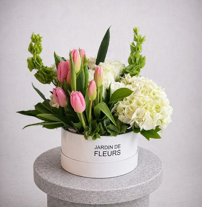 Floral arrangement in a white box labeled 'Jardin de Fleurs' on a gray pedestal.