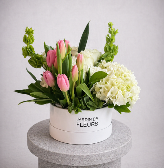 Floral arrangement in a white box labeled 'Jardin de Fleurs' on a gray pedestal.