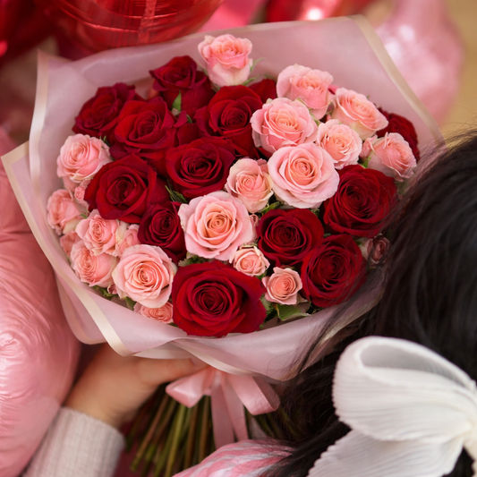 Bouquet of red and pink roses held by a person with blurred background