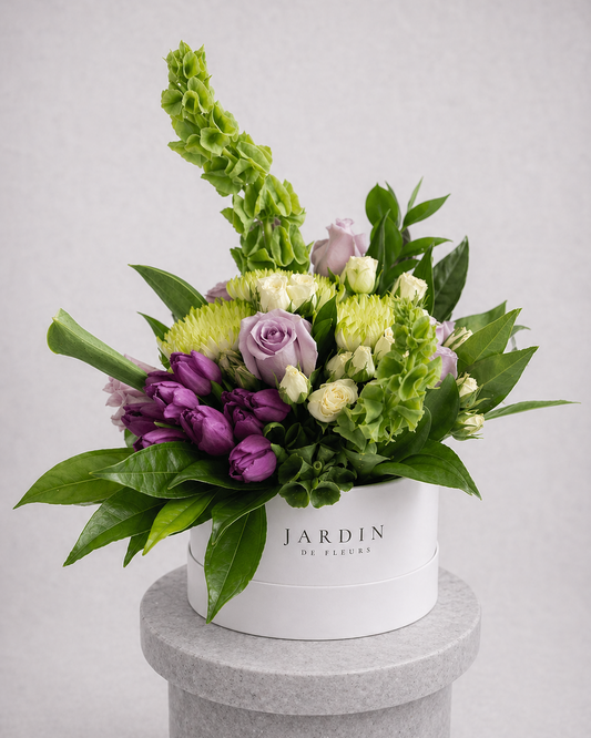 Floral arrangement in a white box labeled 'Jardin' on a gray pedestal against a light gray background