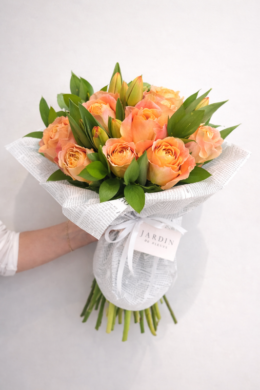 Bouquet of peach-colored roses with green leaves on a white background