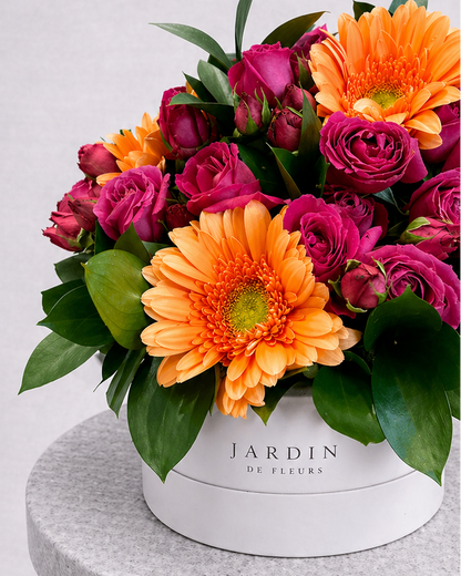 Colorful bouquet of flowers in a white box with 'Jardin de Fleurs' branding on a gray pedestal.